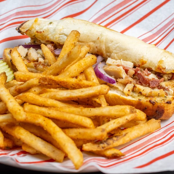 Wise Guys Downtown Italian sub sandwich with chicken, bacon, red onions, and melted cheese, served with fries.