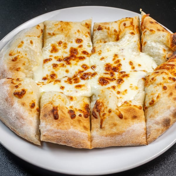 A round, cheesy garlic bread, cut into eight slices, on a white plate.